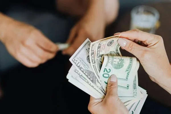 Manos preparando billetes de dólar para una transferencia directa de dinero