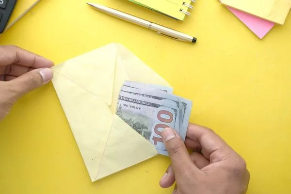 Persona introduciendo dólares en un sobre para una transferencia de dinero