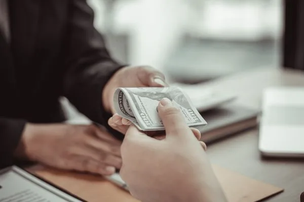 Cliente recibiendo efectivo del cajero durante una transacción de cobro de cheques