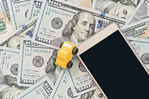 Transferencia segura de dinero mediante dispositivo móvil rodeado de efectivo
