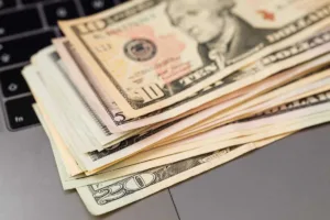 Transferencia de dinero en efectivo colocada en una computadora portátil para su procesamiento