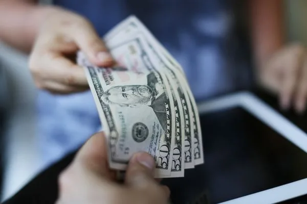 Persona entrega dinero en efectivo en una casa de cambio