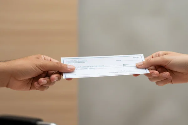 Two hands exchanging a check during a Check Cashing transaction.
