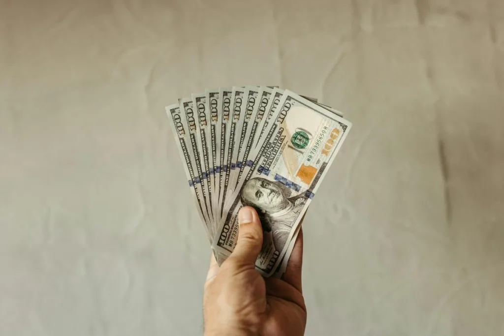 Mano sosteniendo billetes de cien dólares después de una transferencia de dinero