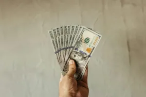 Mano sosteniendo billetes de cien dólares después de una transferencia de dinero