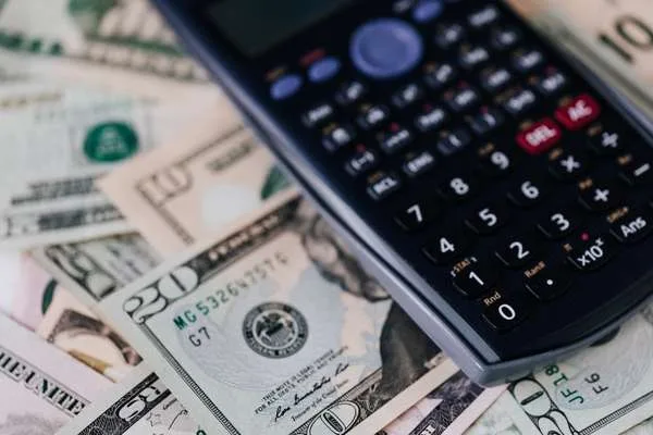 Análisis de cambio de divisas mediante calculadora y billetes de dólares estadounidenses