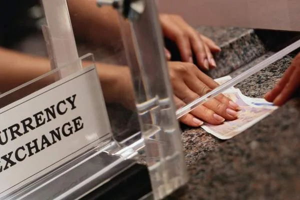 Cliente completando transacción en el mostrador de cambio de divisas