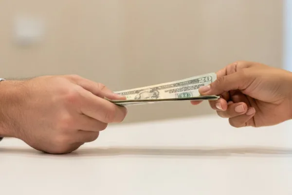 Two hands exchanging cash during a Money Transfer transaction.