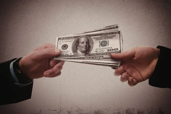 Manos intercambiando efectivo durante una transferencia de dinero en persona