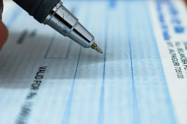 Escritura a lápiz sobre cheques relacionada con el proceso de cobro de cheques