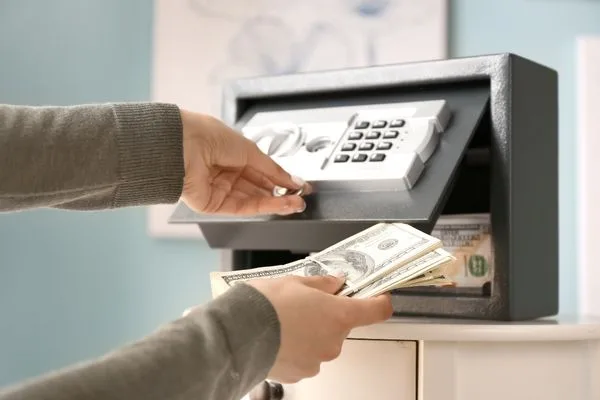 Hands Placing Cash In Safe For Money Order Security