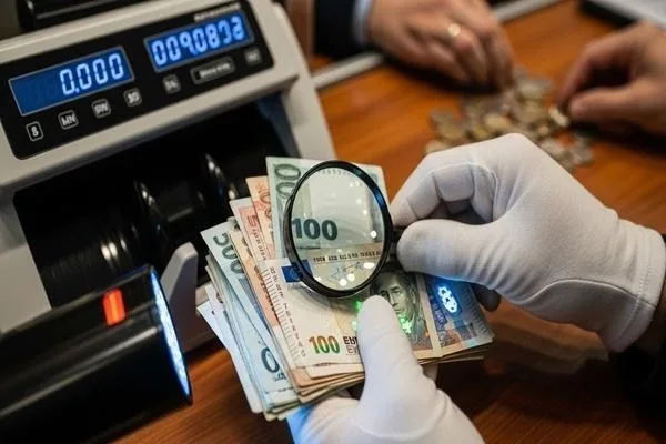 Personal inspeccionando moneda extranjera con lupa para su validación.