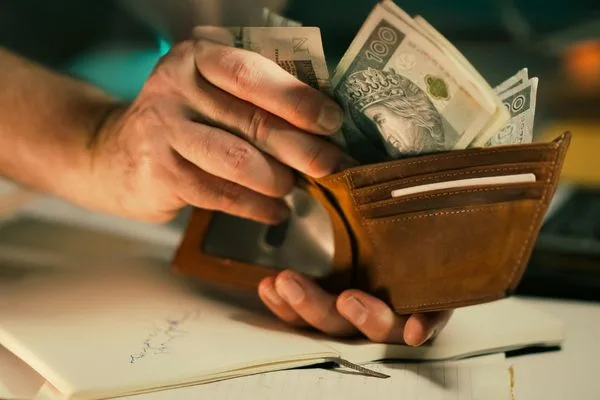 Persona con billetera llena de efectivo para cambio de divisas
