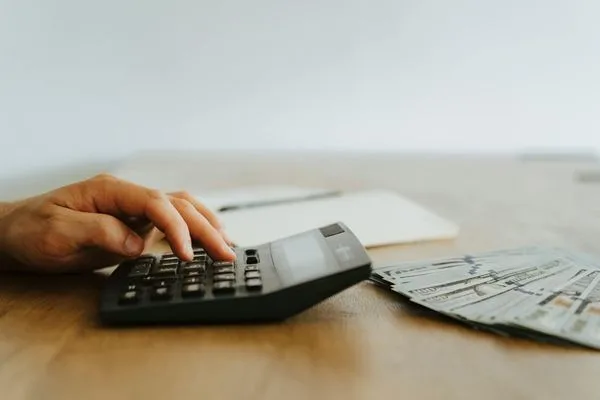 Planificación del cambio de divisas utilizando una calculadora y billetes de dólares estadounidenses