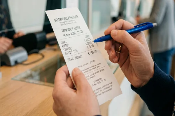 Cliente revisando el recibo en el mostrador de cambio de divisas.
