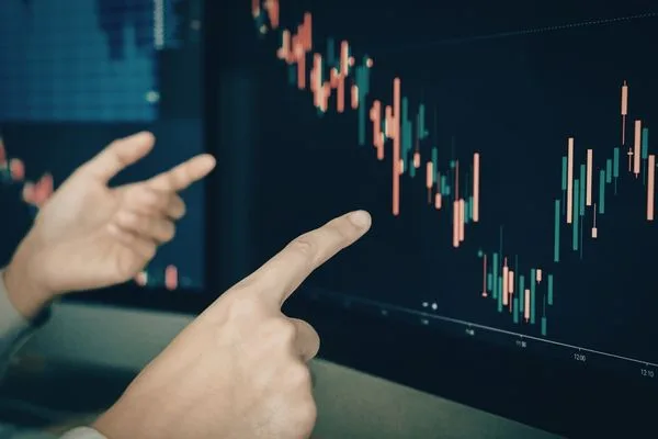 Hands Pointing At Market Graph For Currency Exchange Movements