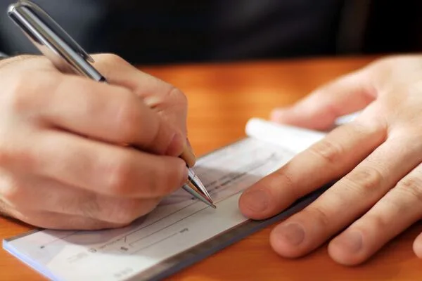 un hombre escribiendo un cheque
