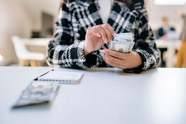 Person Organizing Banknotes For Currency Exchange Transaction At Desk