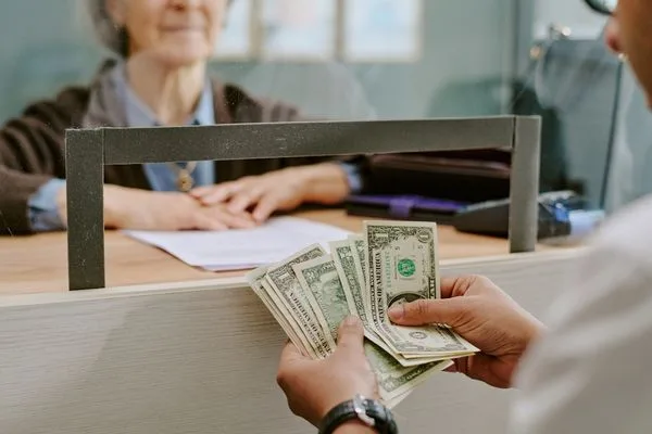 Cliente que recibe cambio de divisas en efectivo en el mostrador de servicio.