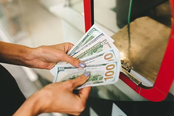 Viajeros que utilizan servicios de cambio de divisas con billetes de dólares estadounidenses.
